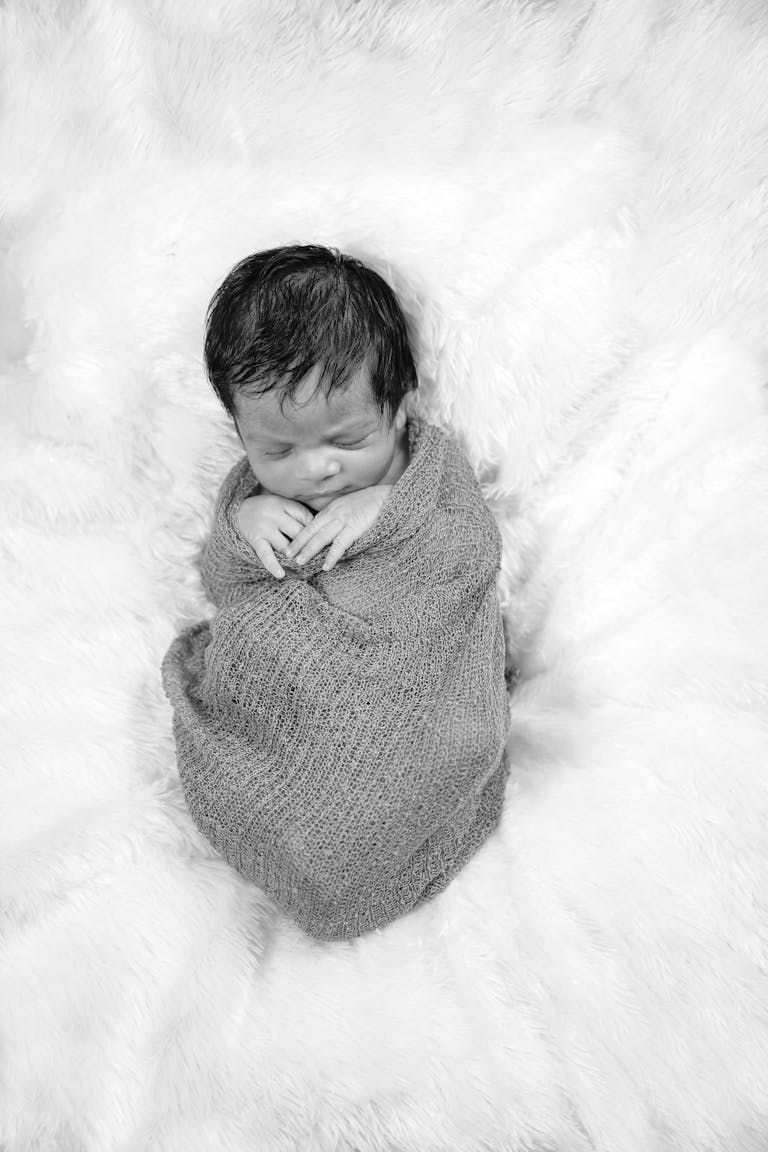 Charming portrait of a newborn baby peacefully asleep in a cozy wrap, showcasing warmth and innocence.
